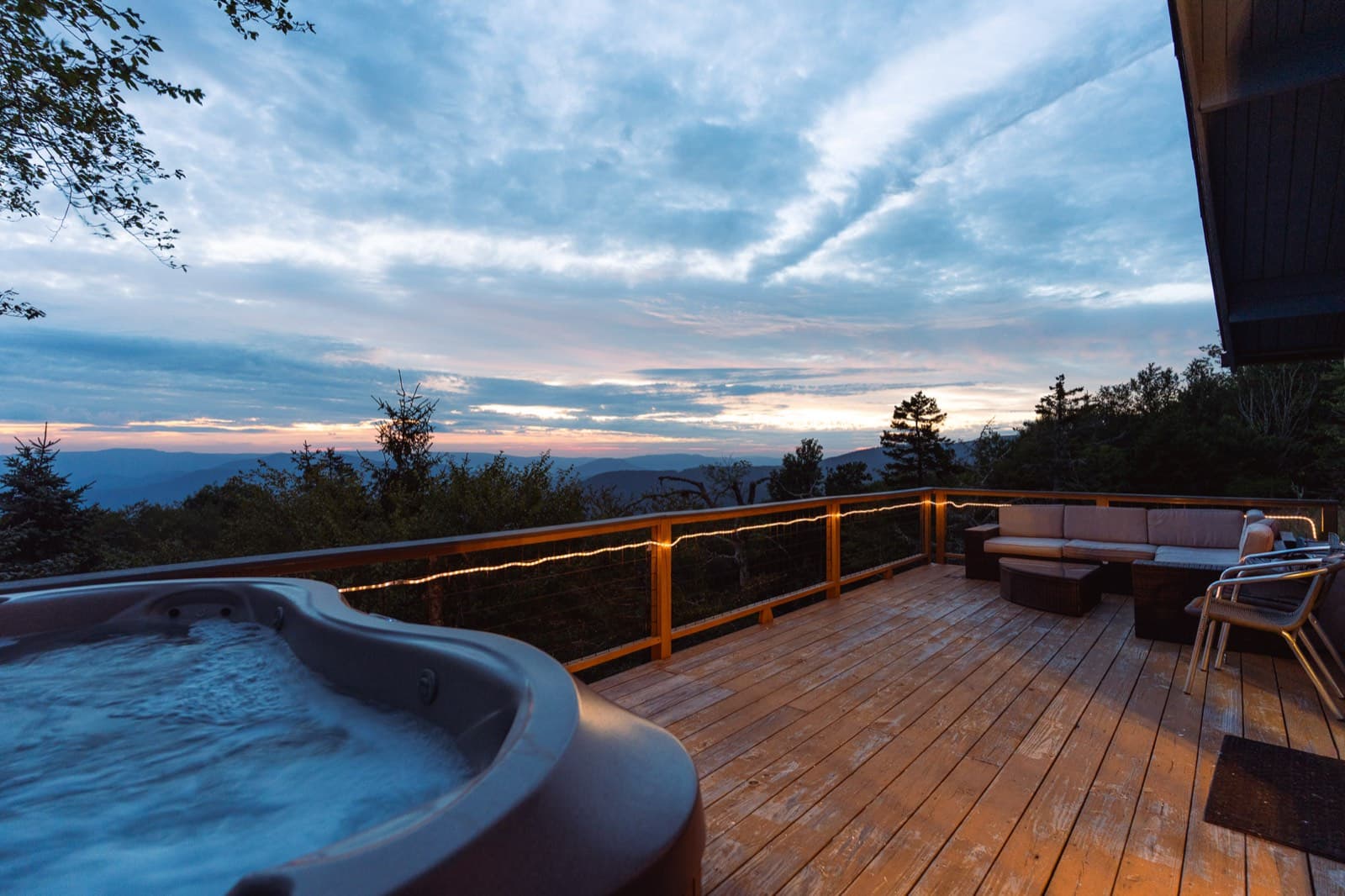 A hot tub on a cabin deck at dusk overlooking the Hocking Hills